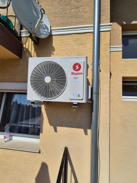 Syen kültéri egység társasház homlokzatán, az ereszcső mellett – klímaszerelés, Balázs Klíma